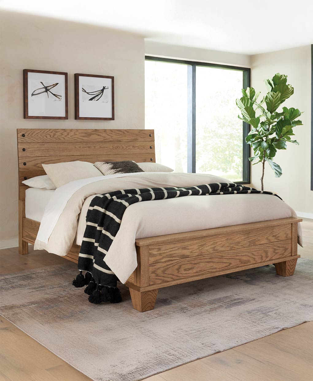 Wooden bed in a bedroom with white bedding and a plant in the corner.