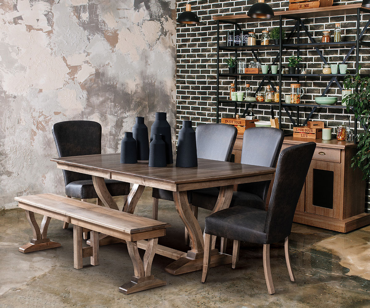 Dining area with wooden table, chairs, and bench against a textured wall and brick shelf.