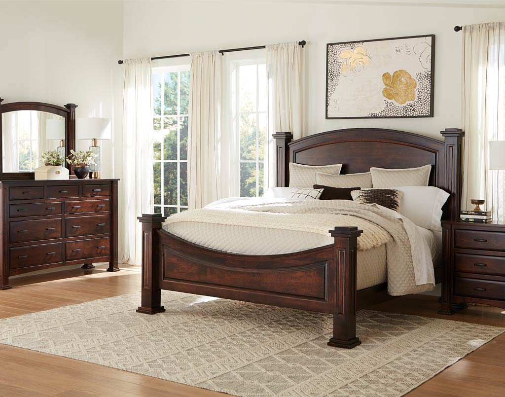 Wooden bedroom set with bed, dresser, and mirror in a well-lit room.
