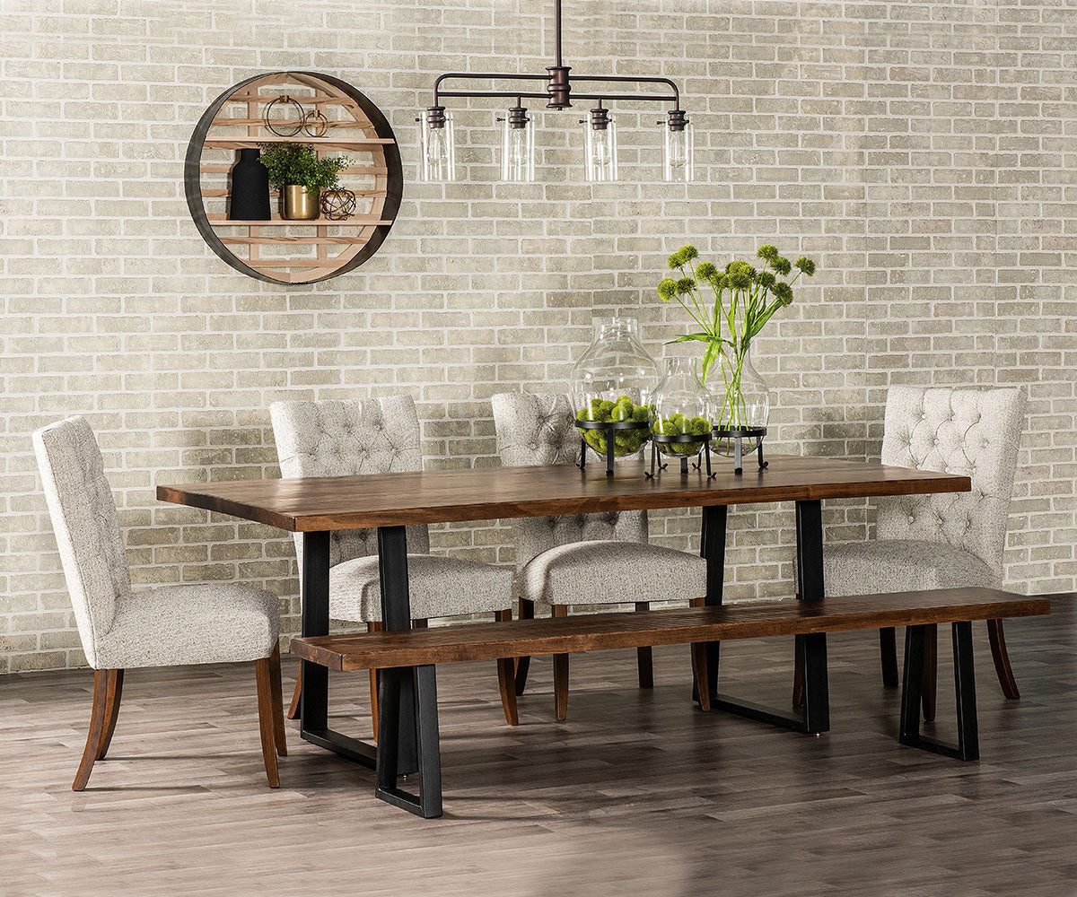 Dining room with wooden table, chairs, and bench against a brick wall.