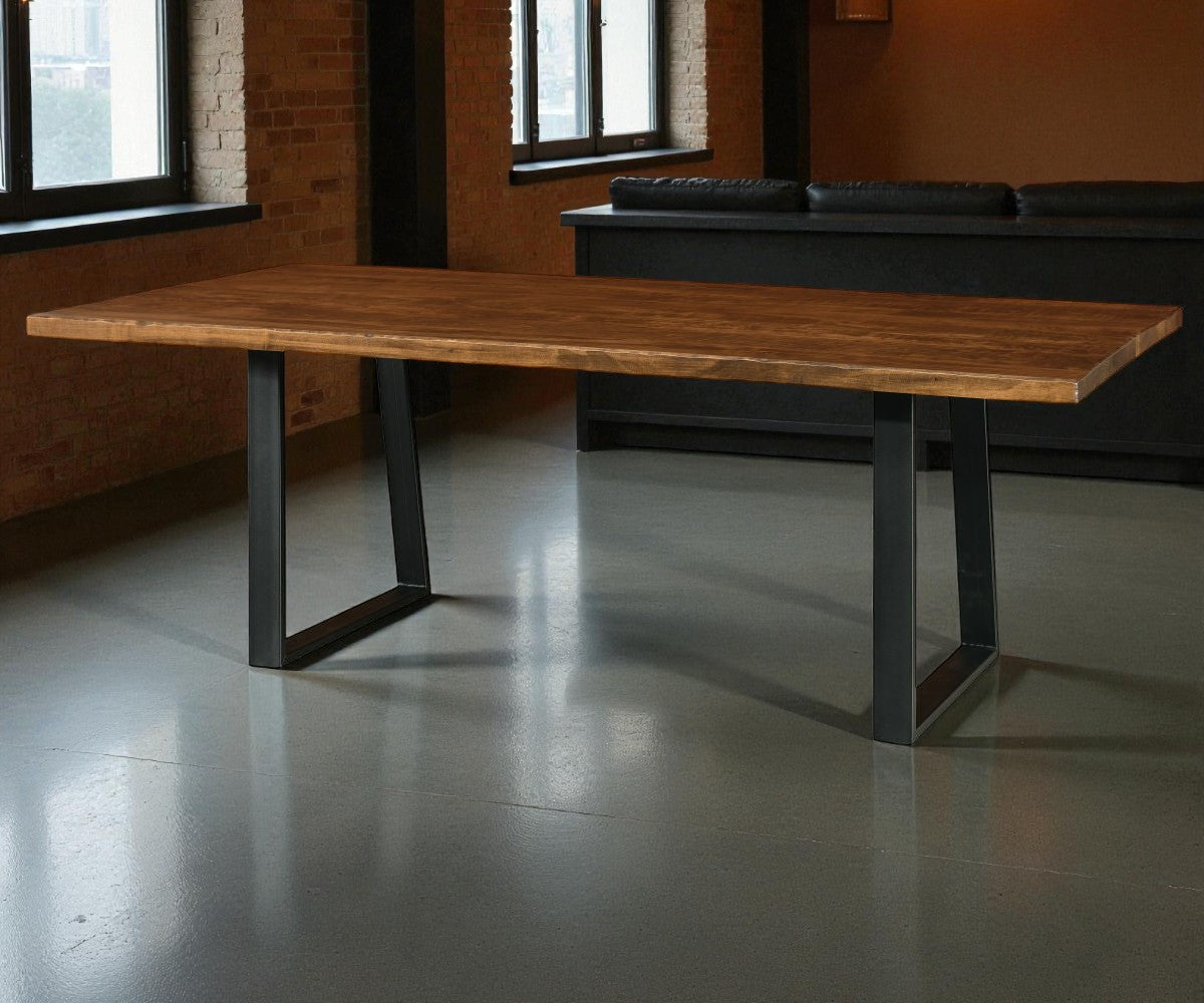 Wooden table with metal legs in a room with brick walls and large windows.