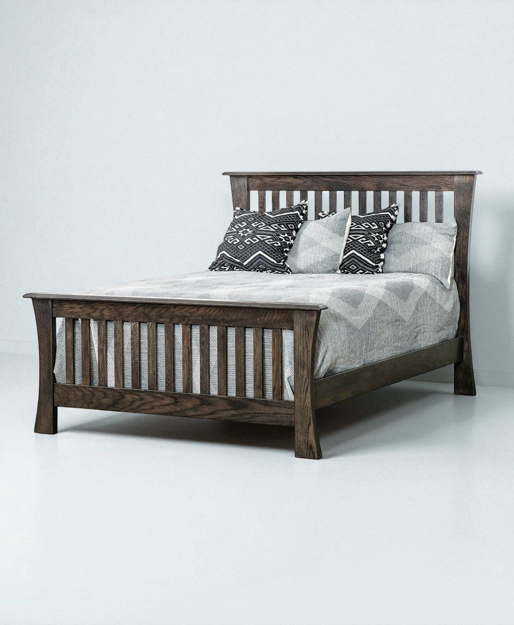Wooden bed with gray bedding and patterned pillows on a white background