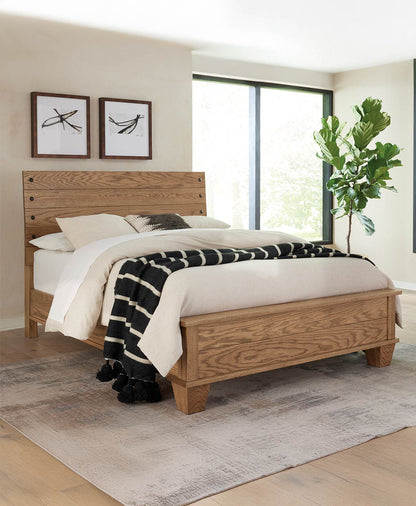 Wooden bed in a bedroom with white bedding and a plant in the corner.