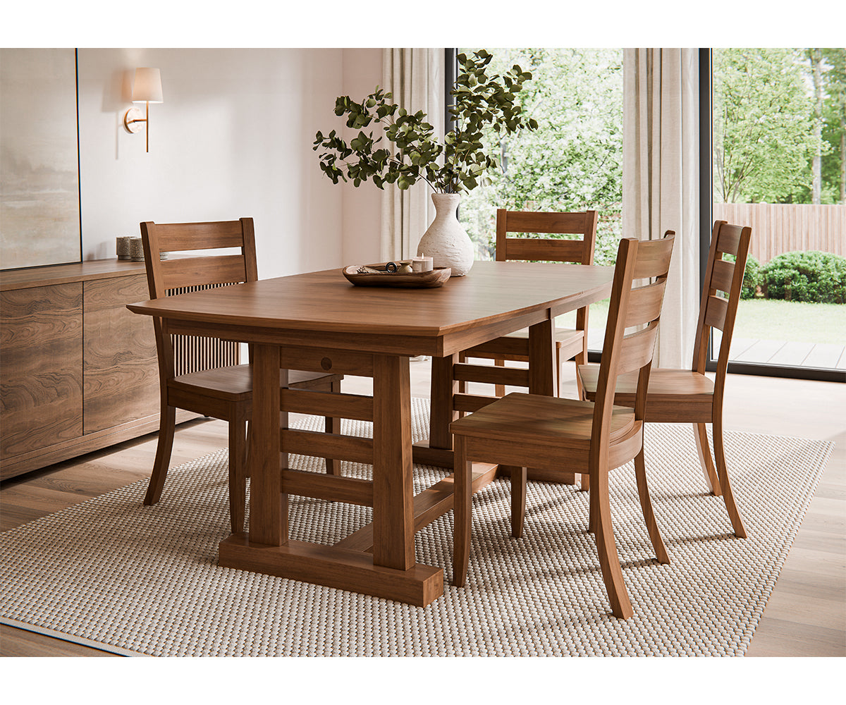 Wooden dining table with chairs in a bright room with large windows.