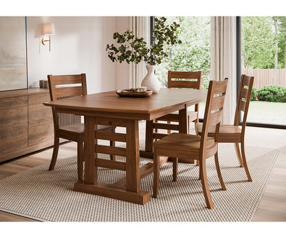 Wooden dining table with chairs in a bright room with large windows.