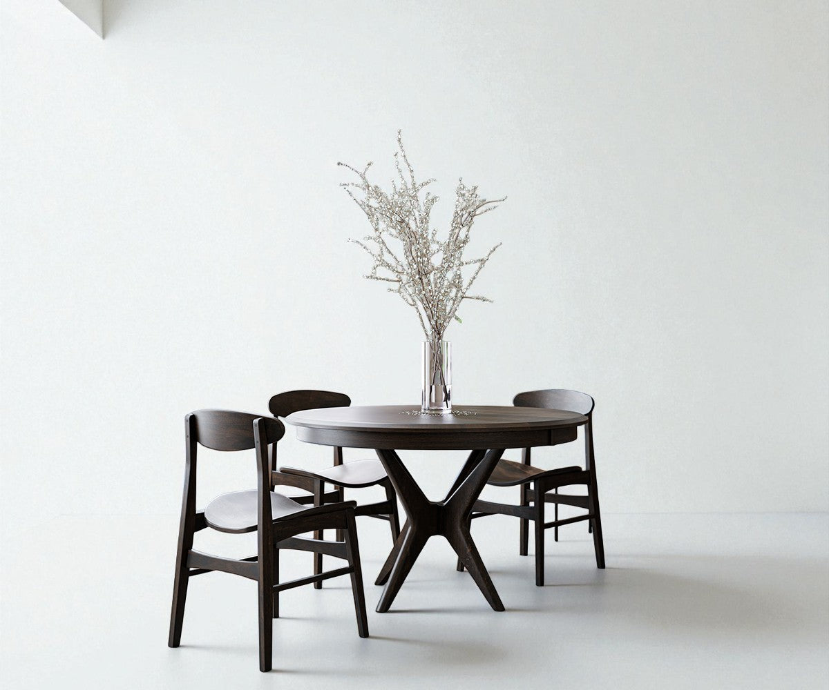 Dark wooden dining table with four chairs against a white wall