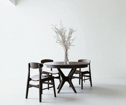 Dark wooden dining table with four chairs against a white wall