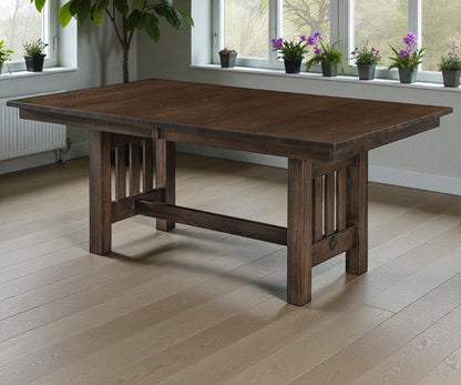 Wooden dining table in a room with large windows and potted plants.